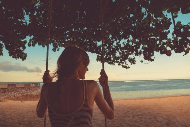 Tropikal bir kumsalda sallanan sevimli genç kız.