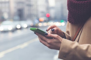 Büyük sokakta geçerken cep telefonu kullanan kız.