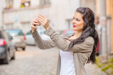 Kentsel ortamda cep telefonu kullanarak sevimli genç kadın.