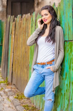 Kentsel ortamda cep telefonu kullanarak sevimli genç kadın.