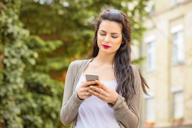 Kentsel ortamda cep telefonu kullanarak sevimli genç kadın.