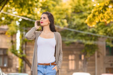 Kentsel ortamda cep telefonu kullanarak sevimli genç kadın.