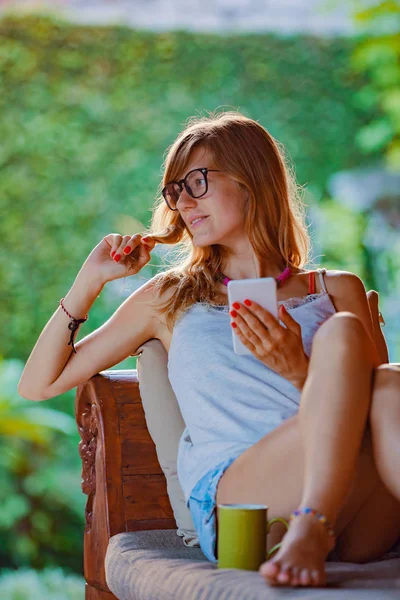 Ung Kvinna Med Hjälp Mobiltelefon Och Dricka Kaffe Verandan Soffa — Stockfoto