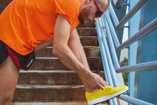 Genç adam bağlama ayakkabı dantel koşu sırasında / excercising.