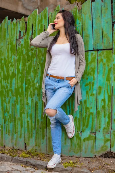 Kentsel ortamda cep telefonu kullanarak sevimli genç kadın.