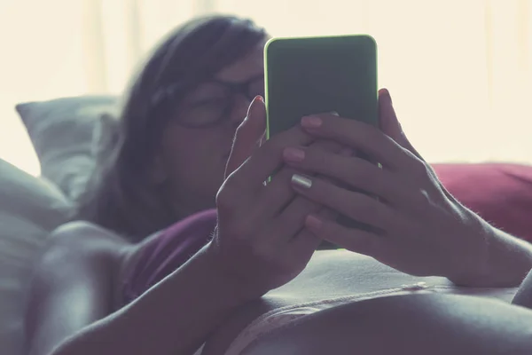在床上有手机的女人 发短信成瘾 — 图库照片