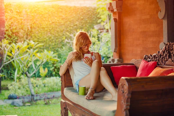 Young Woman Using Cellphone Drinking Coffee Tea Porch Sofa — Stock Photo, Image