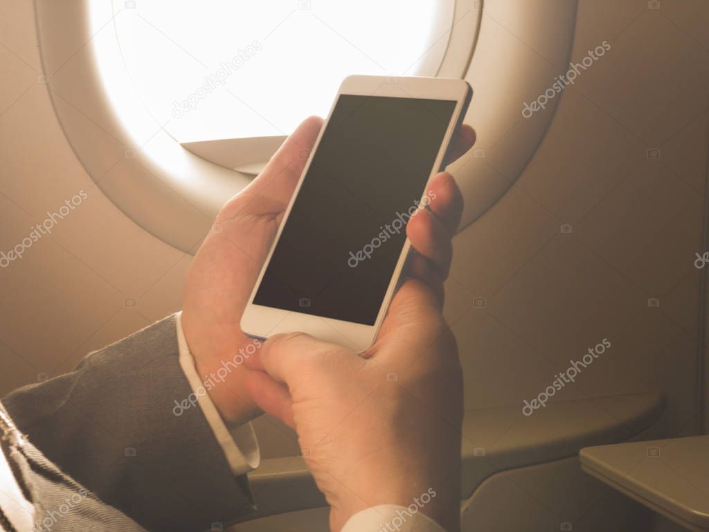 Man using smartphone in the airplane.