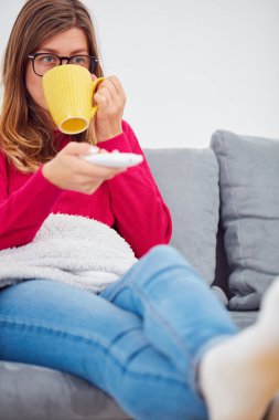 TV uzak tutan kız ve içme kahve / çay bir kanepede.