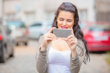 Kentsel ortamda cep telefonu kullanarak sevimli genç kadın.