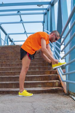 Genç adam bağlama ayakkabı dantel koşu sırasında / excercising.