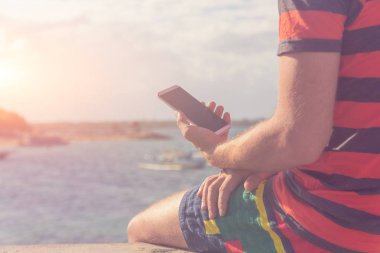 Okyanus kıyısında cep telefonu kullanan adam.