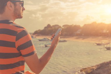 Okyanus kıyısında cep telefonu kullanan adam.