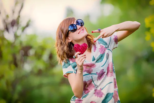 Barış için bir kalp şeklinde işaret ve iki parmak - - semboller tutan Şirin genç kadın.