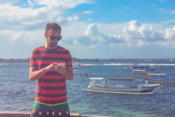 Okyanus kıyısında cep telefonu kullanan adam.