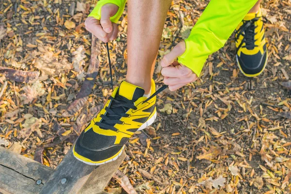 Man tying running shoes in the park. Optical focus is on the shoe.