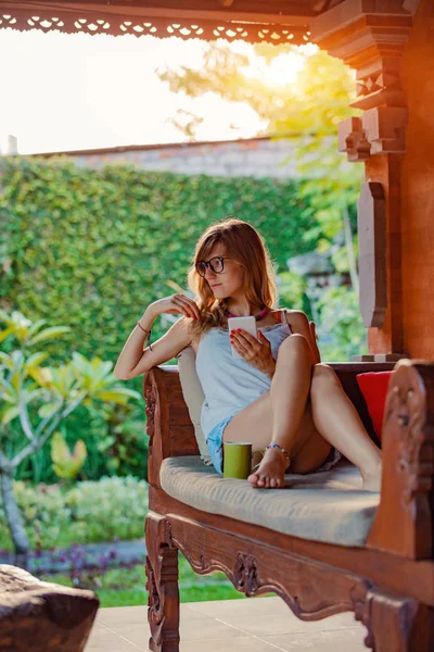 Young Woman Using Cellphone Drinking Coffee Tea Porch Sofa — Stock Photo, Image