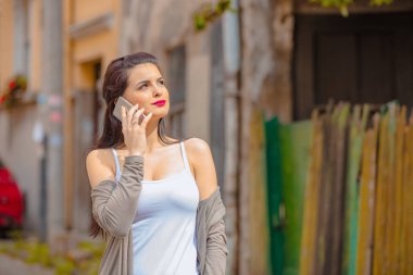 Kentsel ortamda cep telefonu kullanarak sevimli genç kadın.
