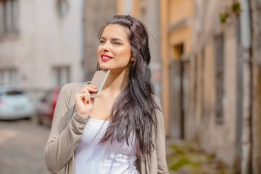 Kentsel ortamda cep telefonu kullanarak sevimli genç kadın.