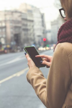 Büyük sokakta geçerken cep telefonu kullanan kız.