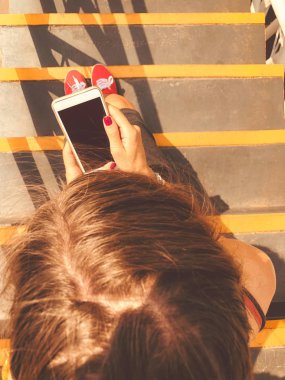 Cep telefonu kullanan kadın / kentsel bir ortamda merdivenlerde otururken smartphone.