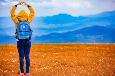 Dağlık manzara modunda kalp şekli sembolü yapma kız.