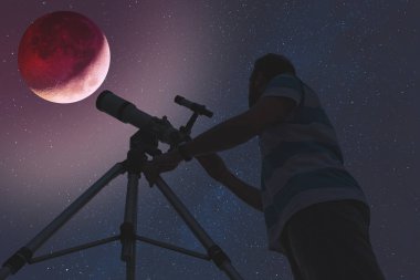 Man looking at lunar eclipse through a telescope. My astronomy work. clipart