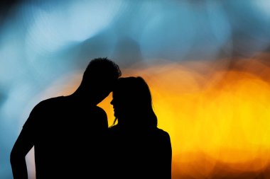 Bir çift ile silüeti de-odaklı / bokeh ışıklar.