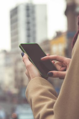 Büyük sokakta geçerken cep telefonu kullanan kız.