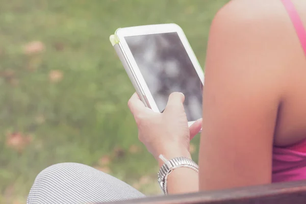 Detail of a woman using tablet in the park.