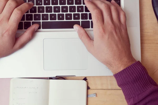 Man hands using laptop and notes, papers.