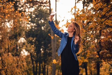 Sevimli kız Park sonbahar renkleri ile cep telefonu kullanarak.