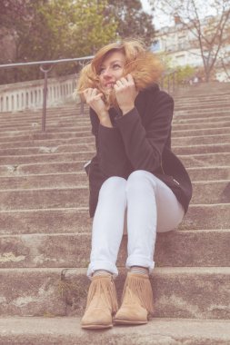 Büyük bir merdivende tek başına oturan tatlı gülen kız..