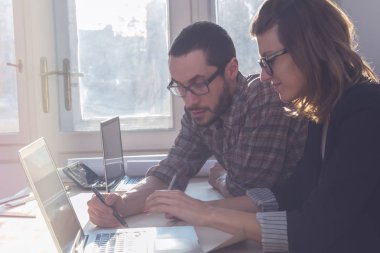 Gençler güneşli ofiste bir proje üzerinde çalışıyor. Adamın yüzünde Optik odaklanma var.