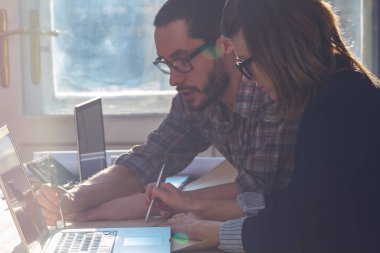 Gençler güneşli ofiste bir proje üzerinde çalışıyor. Kızın yüzünde Optik odaklanma var.