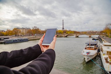 Paris geçmişi ve Eyfel kulesi olan cep telefonu kullanan bir kız..
