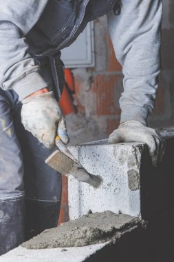 Gerçek inşaat işçisi aletleri kullanarak duvarı örüyor..