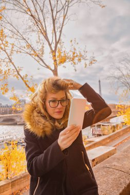 Paris geçmişi ve Eyfel kulesi olan cep telefonu kullanan bir kız..