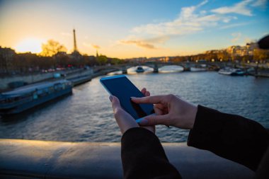 Paris geçmişi ve Eyfel kulesi olan cep telefonu kullanan bir kız..