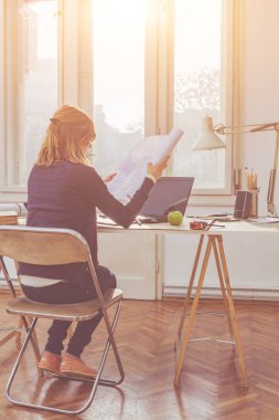 Parlak güneşli oda bir projede çalışan kadın mimar.