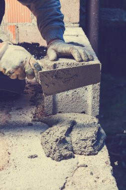 Gerçek inşaat işçisi aletleri kullanarak duvarı örüyor..