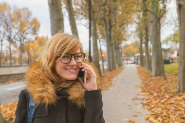 Sonbahar bir ortamda bir kaldırımda yürüyen sevimli kadın.