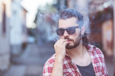 Sokakta sigara içen genç bir adam..