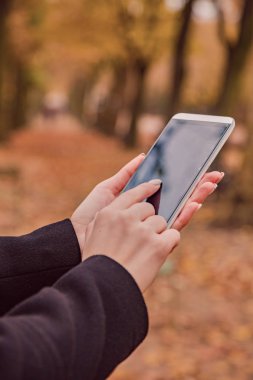 Park sonbahar renkleri ile cep telefonu kullanan kız.