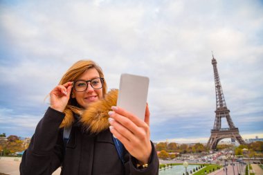 Paris geçmişi ve Eyfel kulesi olan cep telefonu kullanan bir kız..