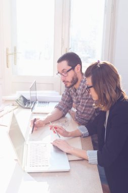 Gençler güneşli ofiste bir proje üzerinde çalışıyor.
