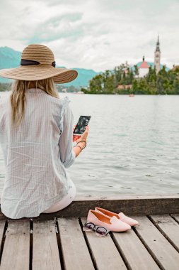 Kız smartphone kullanarak bir ahşap iskele üzerinde.