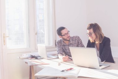 Gençler güneşli ofiste bir proje üzerinde çalışıyor.