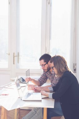 Gençler güneşli ofiste bir proje üzerinde çalışıyor.