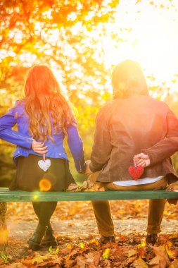 Parkta bir bankta kalp şekli tutan çift.